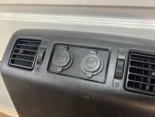 Black center-console panel with two capped 12V outlets between air vents.
