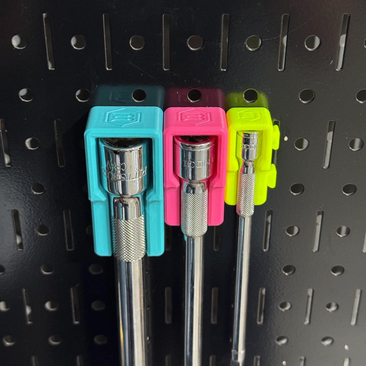 Close-up of teal, pink and yellow extension holders with drive-size markings above the socket ends.