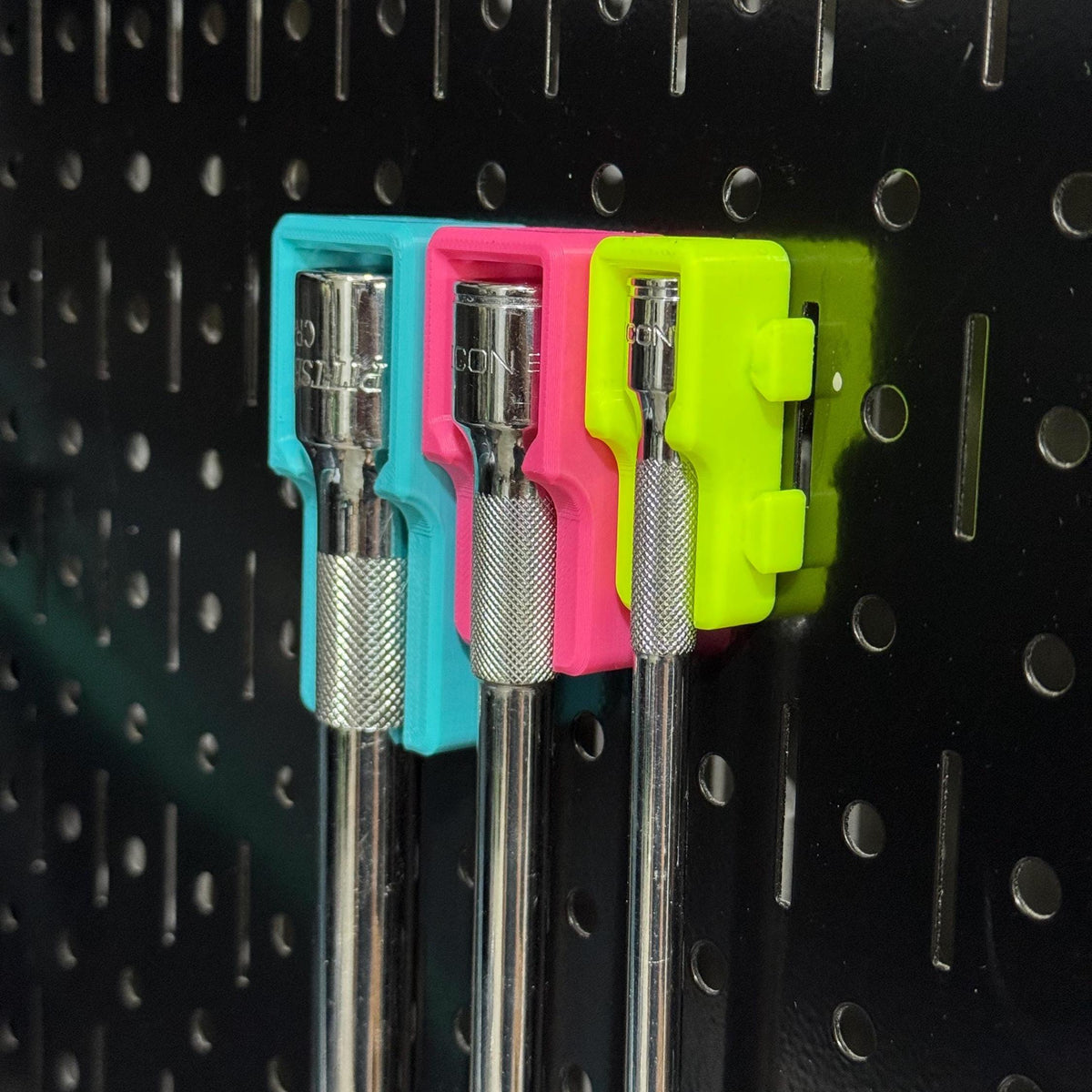 Close-up of socket-extension heads in teal, pink and yellow holders, showing side connector tabs.