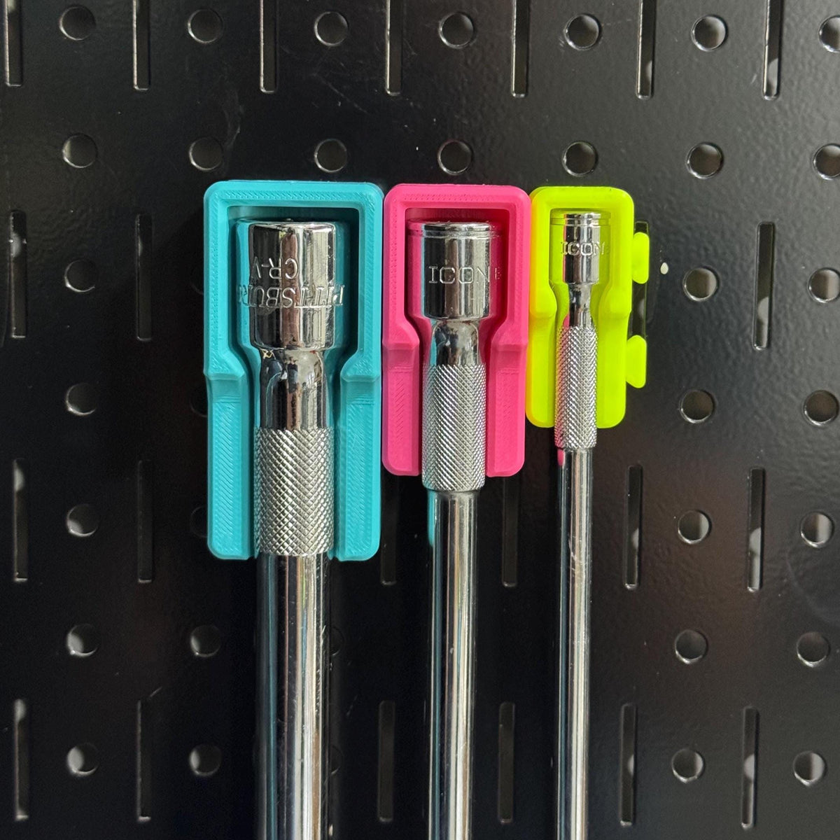 Front close-up of extension heads seated in teal, pink and yellow holders with side tabs.