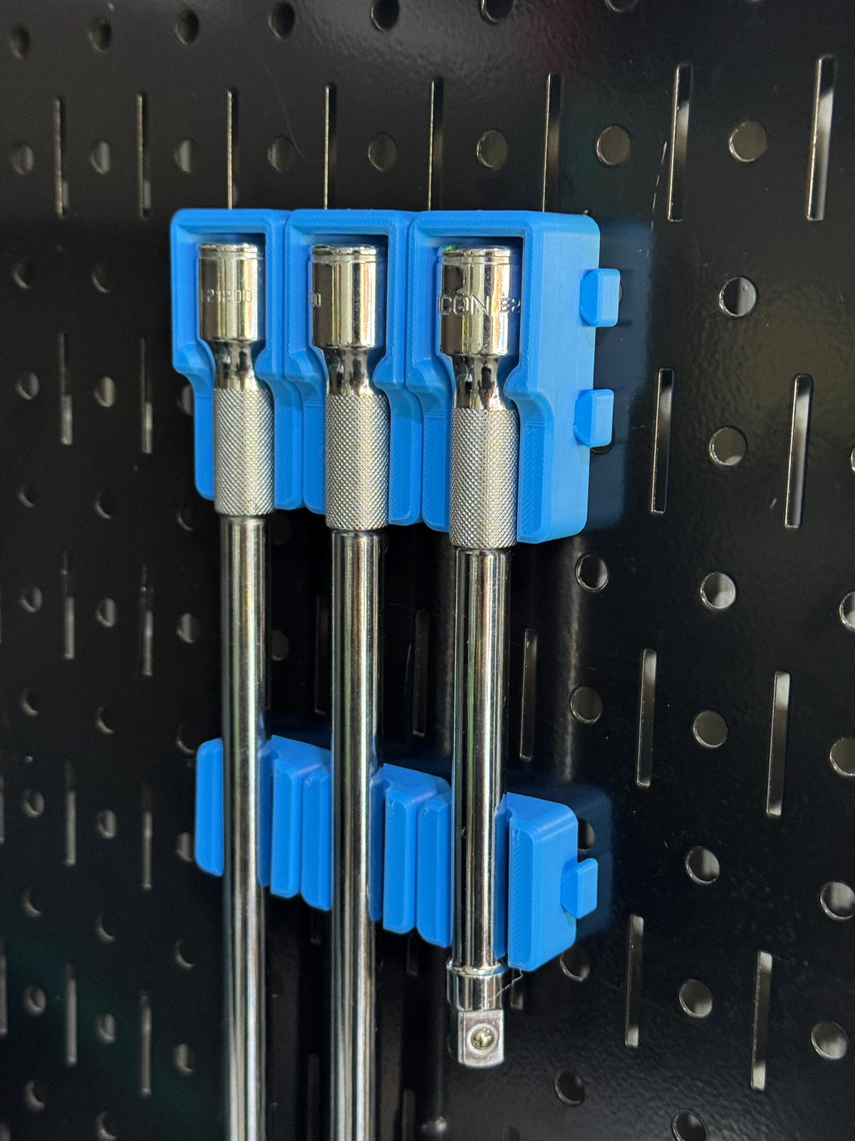 Angled side view of blue extension holders and matching lower support blocks on black pegboard.