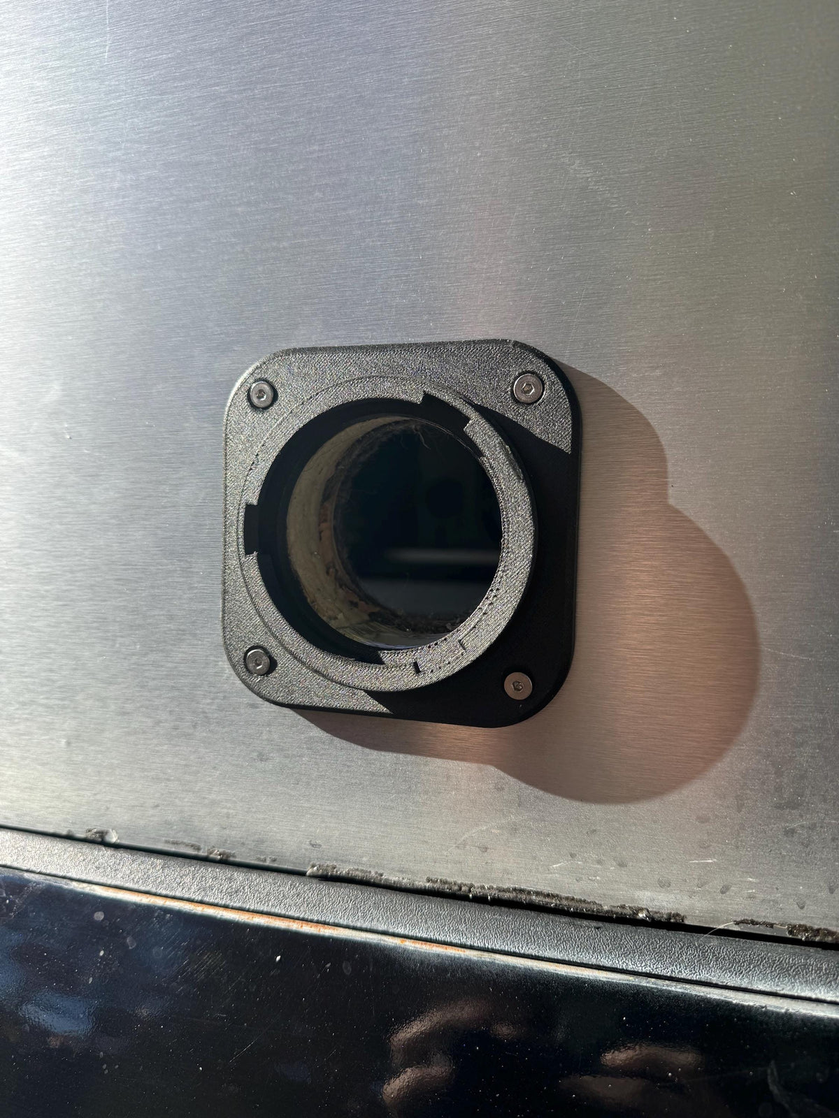 Front view of an uncapped heater wall port on a metal camper panel.