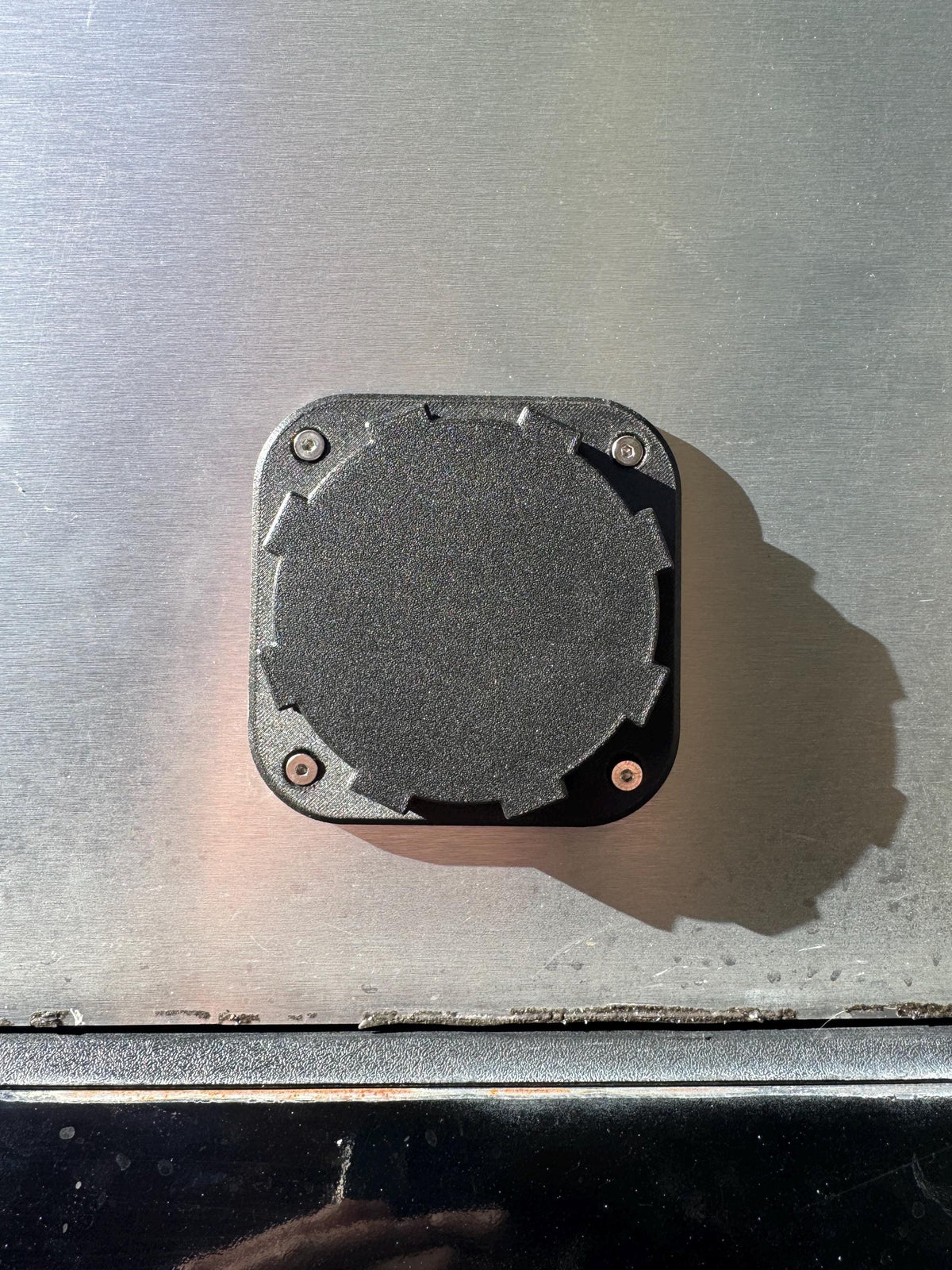 Front view of a closed round cap on the black heater wall port.
