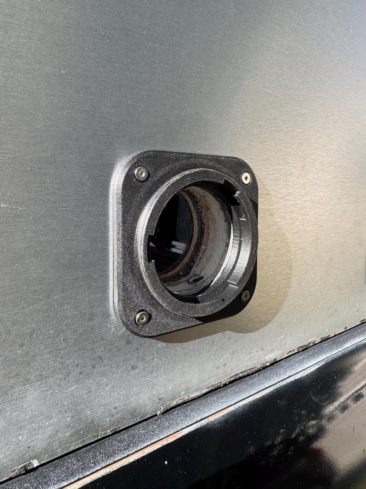 Black heater wall port with the cap removed, showing the open circular connection.